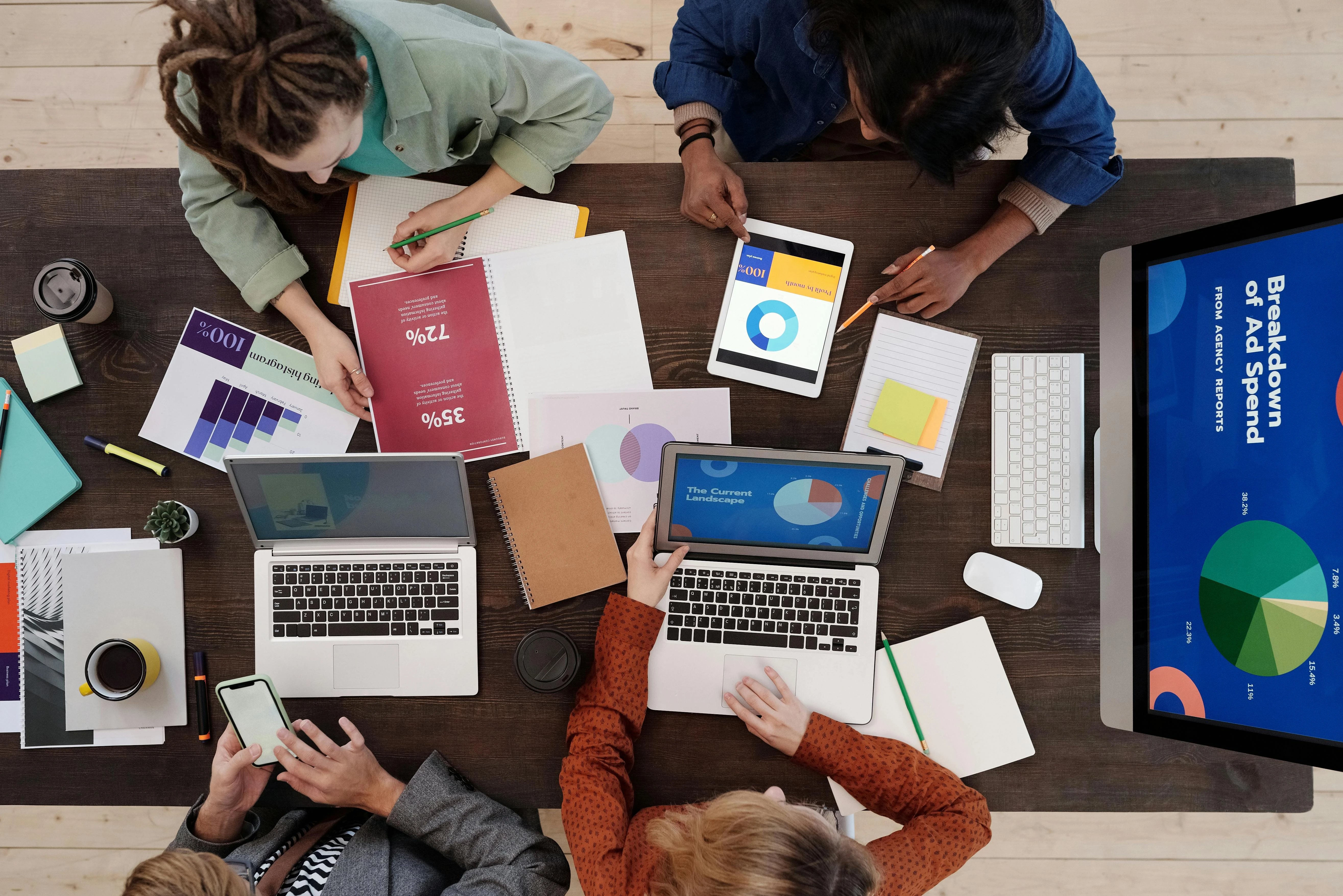 Office with 3 people conducting market research with papers, pens, and computers
