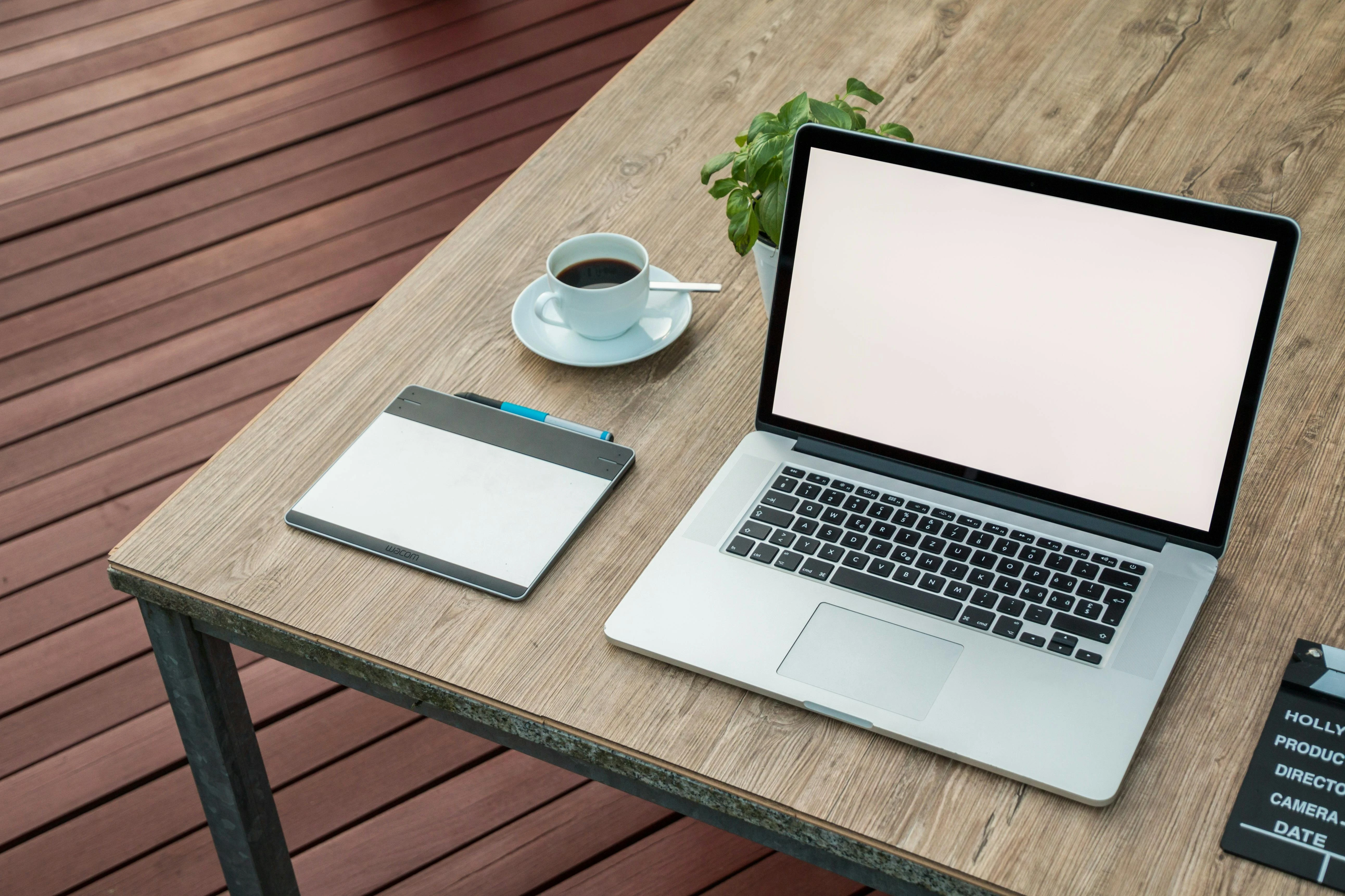 Computer on a desk with coffee and a tablet for taking notes